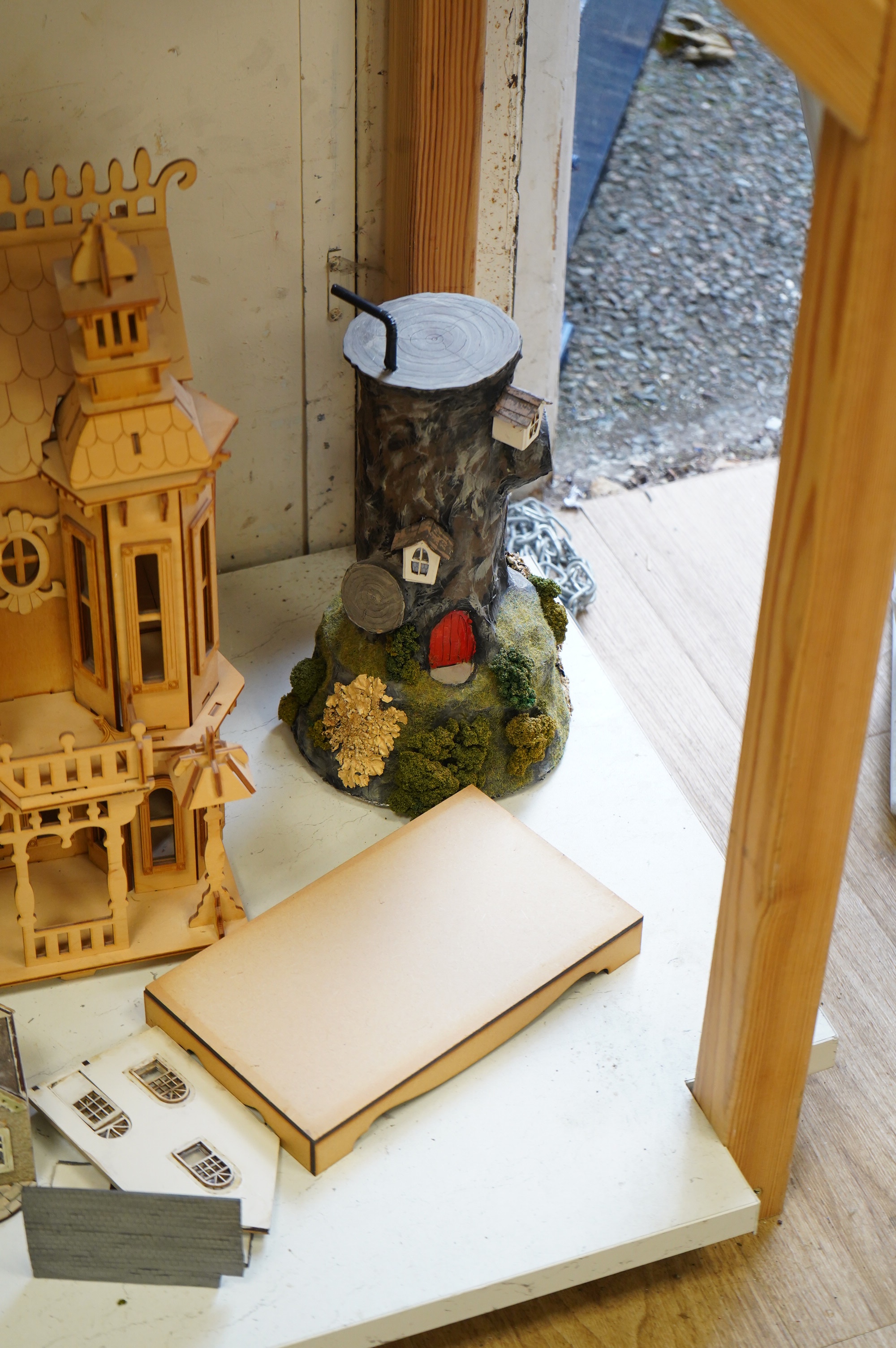 A modern plywood slot together model of a chateau, 50cm high, together with six miniature doll’s houses, a miniature wrought iron garden bench and chair set, and three miniature wooden chairs. Condition - fair.